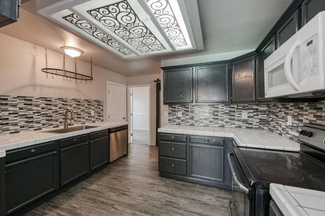 4665 W Yale Ave, Fresno, CA 93722 - kitchen featuring stainless steel appliances, tile counters, tasteful backsplash, and dark wood-style floors