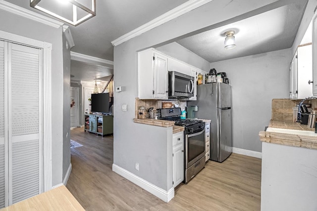 5098 E Ashlan Ave Unit 116, Fresno, CA 93727 - kitchen with stainless steel appliances, light wood-style floors, white cabinets, light countertops, and crown molding
