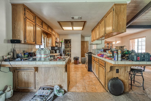 7815 N Sanders Ave, Clovis, CA 93619 - kitchen with a peninsula, stainless steel appliances, tile countertops, a kitchen breakfast bar, and light tile patterned floors