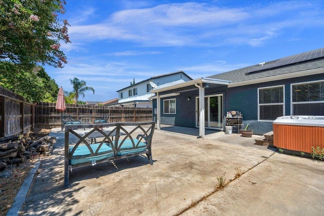 3673 N Denali Ave, Fresno, CA 93727 - rear view of property featuring a hot tub, a patio, a fenced backyard, and solar panels