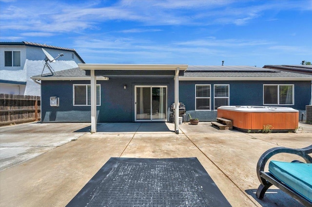 3673 N Denali Ave, Fresno, CA 93727 - rear view of house with a hot tub, a patio, roof mounted solar panels, stucco siding, and roof with shingles