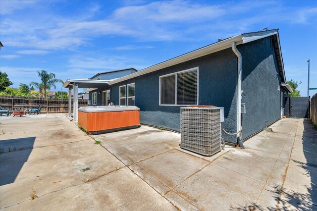3673 N Denali Ave, Fresno, CA 93727 - rear view of property with a hot tub, a patio, a fenced backyard, and stucco siding