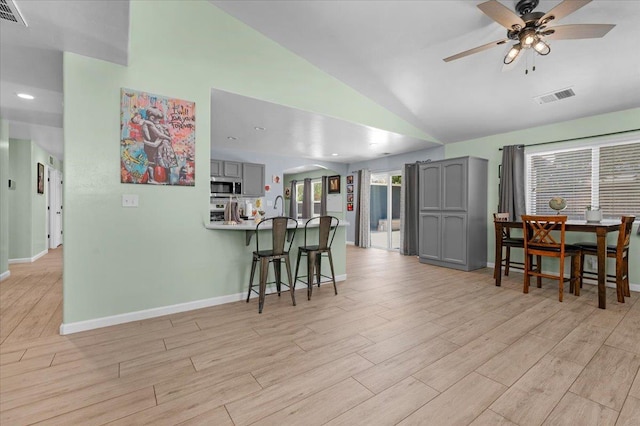 3673 N Denali Ave, Fresno, CA 93727 - kitchen with gray cabinetry, stainless steel microwave, arched walkways, a ceiling fan, and a kitchen bar