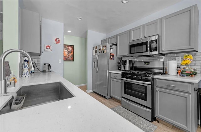 3673 N Denali Ave, Fresno, CA 93727 - kitchen featuring appliances with stainless steel finishes, gray cabinets, light wood-type flooring, tasteful backsplash, and recessed lighting