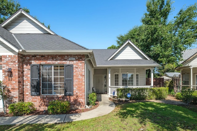 10223 N Price Ave, Fresno, CA 93730 - view of front of house with brick siding, a front lawn, covered porch, and a shingled roof