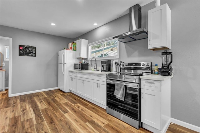 1408 S Hope Ave, Reedley, CA 93654 - kitchen with stainless steel appliances, wall chimney range hood, light countertops, white cabinets, and recessed lighting