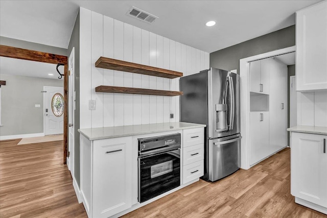 1408 S Hope Ave, Reedley, CA 93654 - kitchen with black oven, stainless steel refrigerator with ice dispenser, open shelves, white cabinets, and light wood-type flooring