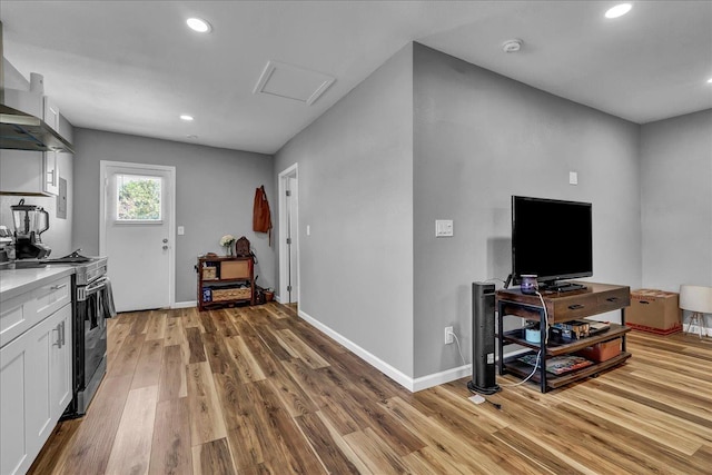 1408 S Hope Ave, Reedley, CA 93654 - kitchen with stainless steel electric range oven, light wood-style flooring, wall chimney exhaust hood, white cabinets, and recessed lighting