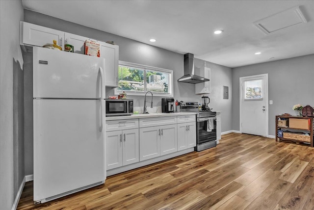 1408 S Hope Ave, Reedley, CA 93654 - kitchen with stainless steel appliances, wall chimney exhaust hood, white cabinetry, light wood finished floors, and recessed lighting
