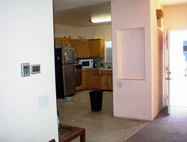 34937 Bronco Ln, Yokuts Valley, CA 93675 - kitchen featuring freestanding refrigerator, white microwave, and brown cabinets