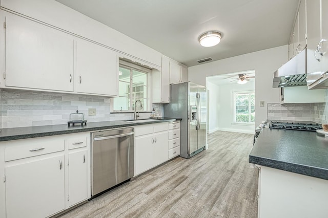 927 W Pico Ave, Fresno, CA 93705 - kitchen with appliances with stainless steel finishes, light wood finished floors, white cabinetry, tasteful backsplash, and dark countertops