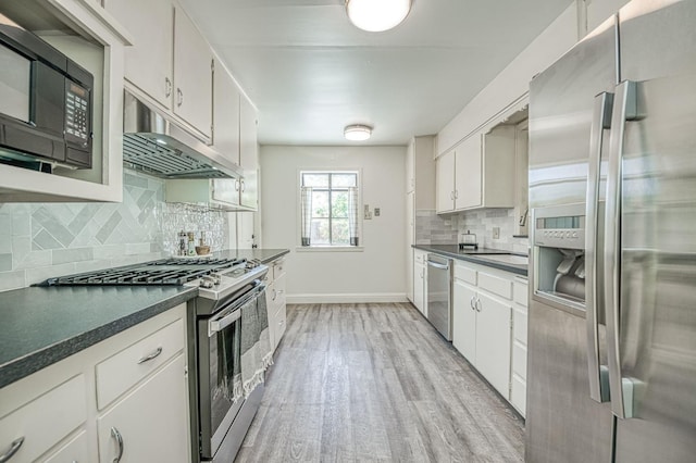 927 W Pico Ave, Fresno, CA 93705 - kitchen with appliances with stainless steel finishes, under cabinet range hood, light wood-style floors, dark countertops, and backsplash
