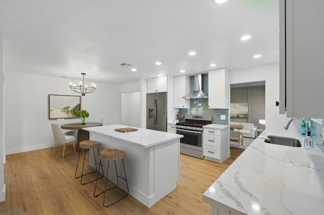 2712 Westgate Dr, Madera, CA 93637 - kitchen featuring stainless steel range oven, refrigerator with ice dispenser, wall chimney range hood, a center island, and a breakfast bar