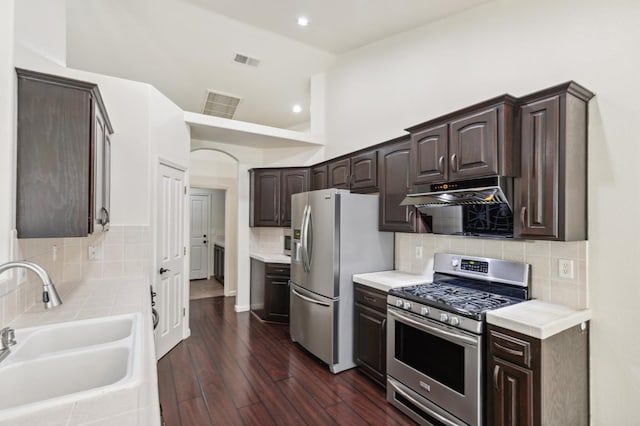 1158 E Hogan Ave, Fresno, CA 93730 - kitchen with stainless steel appliances, dark brown cabinets, under cabinet range hood, tasteful backsplash, and dark wood finished floors
