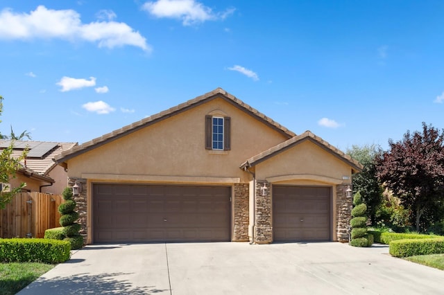 1158 E Hogan Ave, Fresno, CA 93730 - view of front facade featuring stucco siding, stone siding, an attached garage, concrete driveway, and a tiled roof