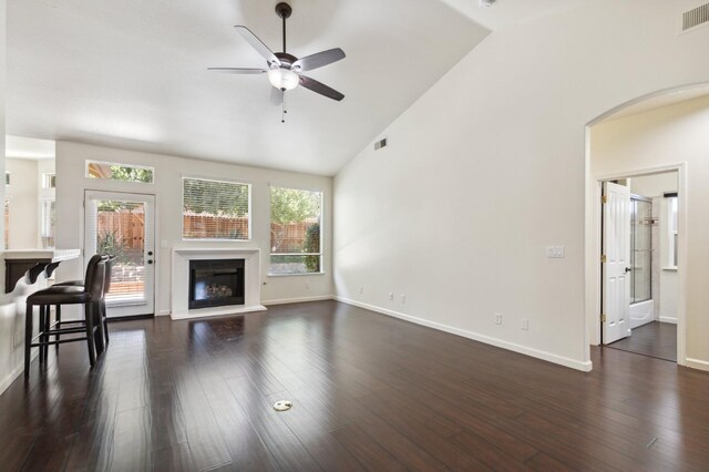 1158 E Hogan Ave, Fresno, CA 93730 - unfurnished living room with a ceiling fan, a glass covered fireplace, dark wood finished floors, arched walkways, and high vaulted ceiling