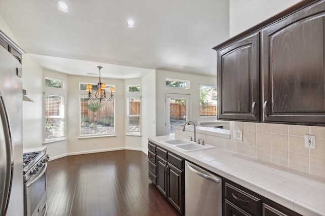 1158 E Hogan Ave, Fresno, CA 93730 - kitchen with stainless steel appliances, dark brown cabinets, tile countertops, a chandelier, and dark wood finished floors