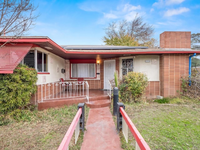 3110 N Del Mar Ave, Fresno, CA 93704 - view of front facade featuring a porch, solar panels, stucco siding, and a chimney