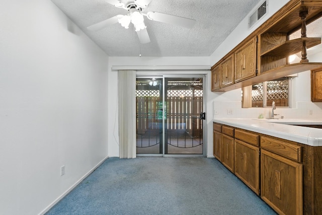 4909 N 7th St Unit S, Fresno, CA 93726 - kitchen featuring open shelves, a textured ceiling, brown cabinets, light countertops, and decorative backsplash
