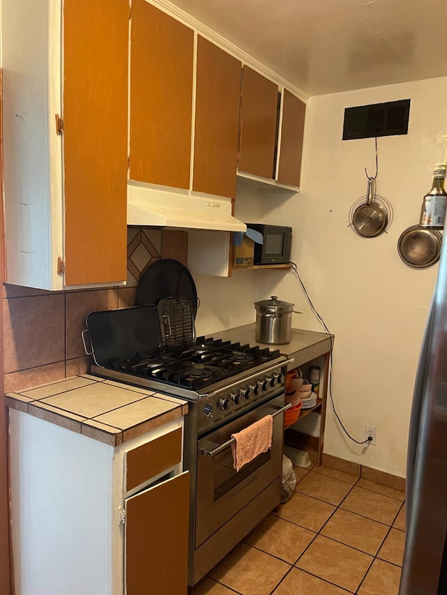 826 N W St, Visalia, CA 93291 - kitchen featuring high end stove, under cabinet range hood, light tile patterned floors, backsplash, and light countertops