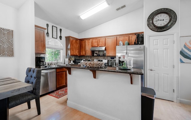 2148 N Ivanhoe Ave, Fresno, CA 93722 - kitchen featuring stainless steel appliances, under cabinet range hood, light wood finished floors, vaulted ceiling, and backsplash