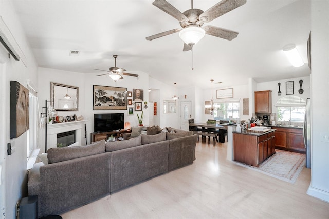2148 N Ivanhoe Ave, Fresno, CA 93722 - living area with a glass covered fireplace, ceiling fan, vaulted ceiling, and light wood-style flooring