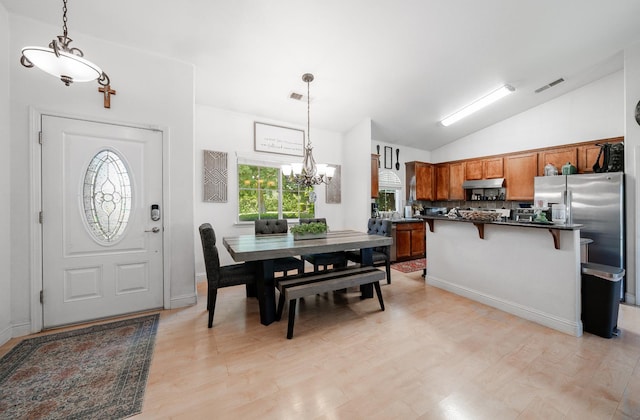 2148 N Ivanhoe Ave, Fresno, CA 93722 - dining space featuring a chandelier, vaulted ceiling, and light wood-style floors