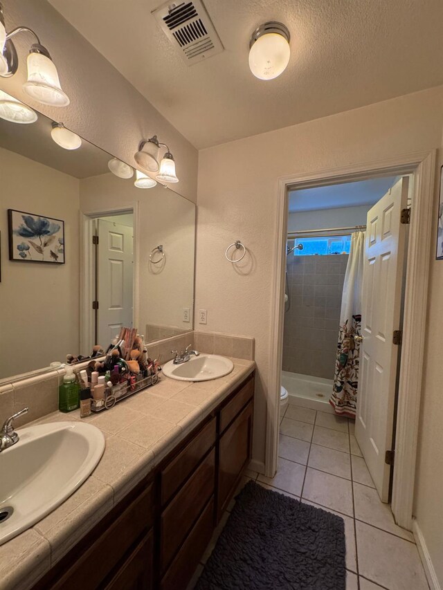 605 W Russell Ave, Visalia, CA 93277 - bathroom with a tile shower, double vanity, and tile patterned floors