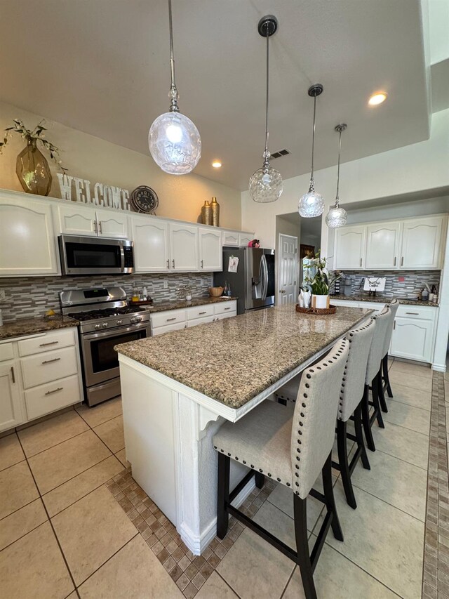 605 W Russell Ave, Visalia, CA 93277 - kitchen with appliances with stainless steel finishes, tasteful backsplash, a center island, dark stone counters, and white cabinetry