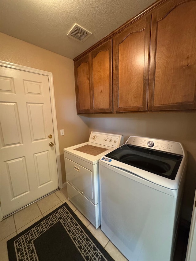605 W Russell Ave, Visalia, CA 93277 - washroom featuring washing machine and dryer, cabinet space, light tile patterned floors, and a textured ceiling