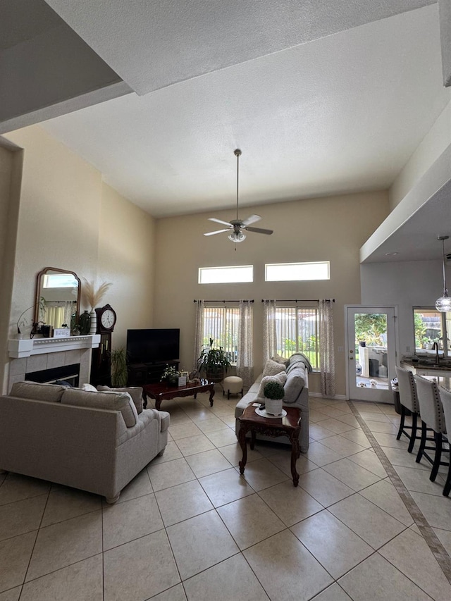 605 W Russell Ave, Visalia, CA 93277 - living room featuring light tile patterned floors, ceiling fan, a fireplace, and a high ceiling