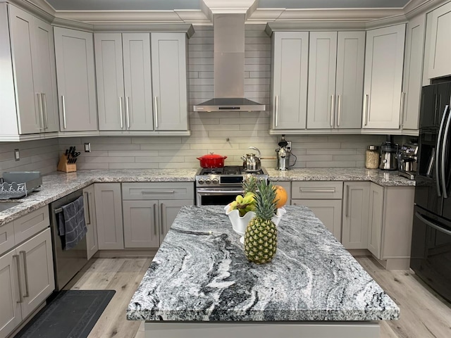 kitchen with wall chimney exhaust hood, stainless steel appliances, gray cabinets, light wood finished floors, and decorative backsplash