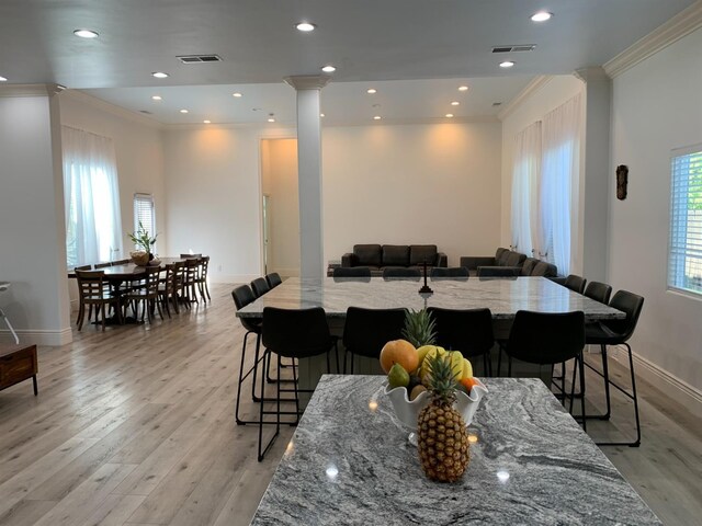 dining room with ornamental molding, light wood-type flooring, recessed lighting, and ornate columns