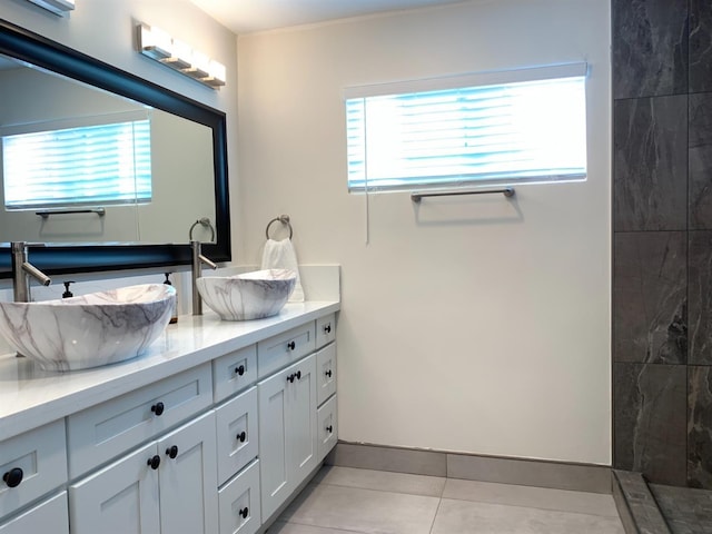 bathroom with double vanity, tile patterned flooring, and tiled shower