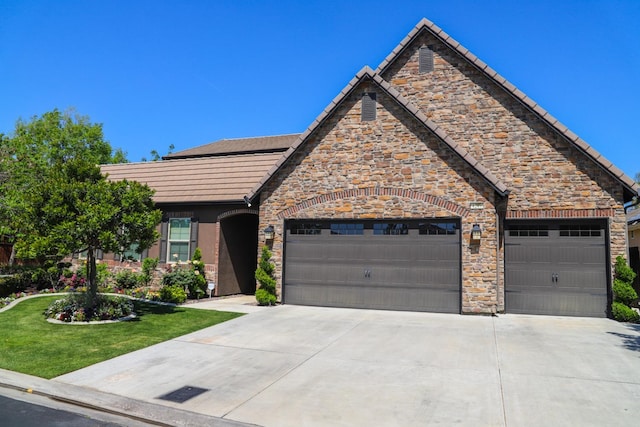 4249 N Waterside Dr, Clovis, CA 93619 - view of front of home with driveway, a tiled roof, stone siding, an attached garage, and a front yard