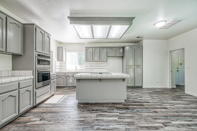 1224 Oak Ave, Clovis, CA 93611 - kitchen featuring tile counters, gray cabinets, double oven, and dark wood-type flooring