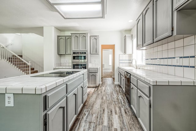 1224 Oak Ave, Clovis, CA 93611 - kitchen featuring stainless steel appliances, gray cabinets, tile counters, wood finished floors, and decorative backsplash