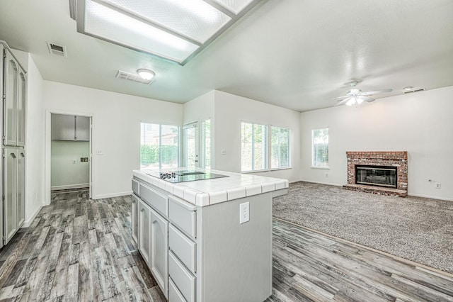 1224 Oak Ave, Clovis, CA 93611 - kitchen featuring tile counters, wood finished floors, ceiling fan, and a brick fireplace