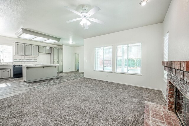 1224 Oak Ave, Clovis, CA 93611 - unfurnished living room with a ceiling fan, a brick fireplace, carpet floors, and wood finished floors