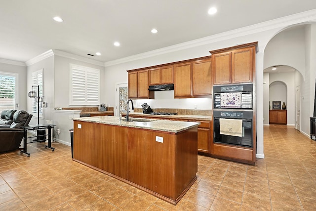 17024 Granite Falls Way, Chowchilla, CA 93610 - kitchen featuring under cabinet range hood, brown cabinetry, light stone countertops, crown molding, and light tile patterned flooring