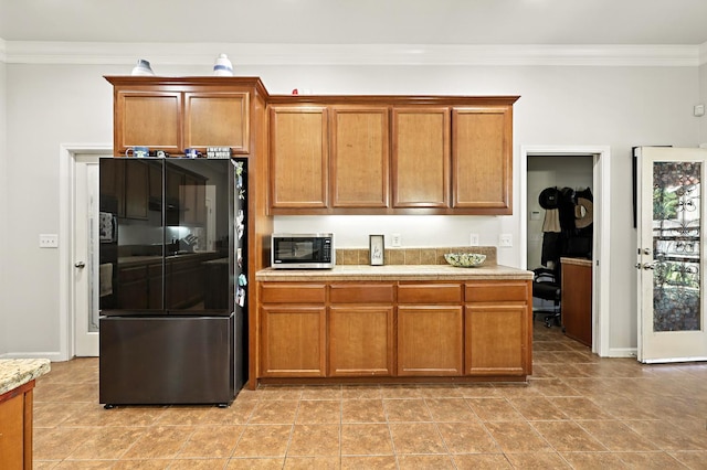 17024 Granite Falls Way, Chowchilla, CA 93610 - kitchen with smart refrigerator, stainless steel microwave, crown molding, light countertops, and brown cabinetry
