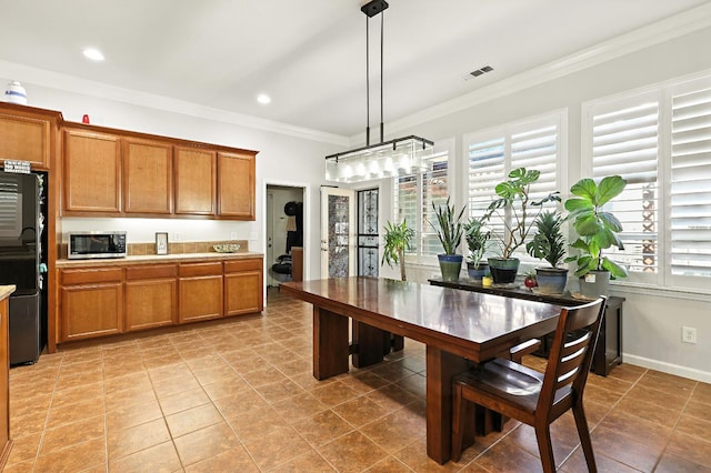 17024 Granite Falls Way, Chowchilla, CA 93610 - kitchen featuring freestanding refrigerator, stainless steel microwave, healthy amount of natural light, brown cabinetry, and crown molding