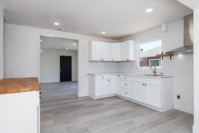 2012 E Clinton Ave, Fresno, CA 93703 - kitchen with wall chimney range hood, light wood-style floors, decorative backsplash, white cabinets, and recessed lighting