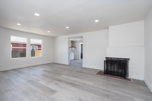 2012 E Clinton Ave, Fresno, CA 93703 - unfurnished living room with light wood-type flooring, a brick fireplace, and recessed lighting