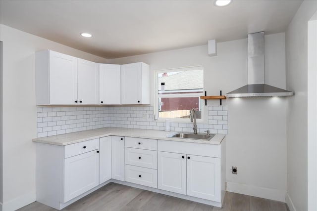 2012 E Clinton Ave, Fresno, CA 93703 - kitchen with wall chimney range hood, white cabinetry, light wood finished floors, light countertops, and recessed lighting