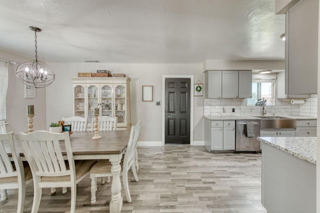 447 W Scott Ave, Clovis, CA 93612 - dining area featuring light wood-style flooring, a chandelier, and a textured ceiling