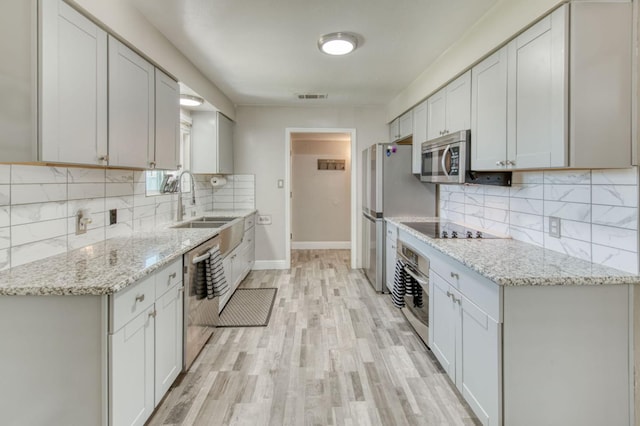447 W Scott Ave, Clovis, CA 93612 - kitchen with stainless steel appliances, decorative backsplash, light wood-style floors, and light stone countertops
