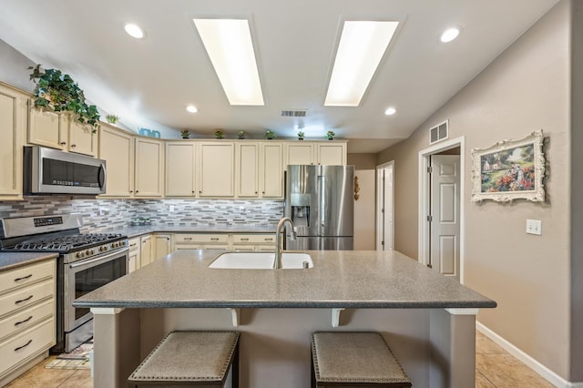 3624 N Jackie, Visalia, CA 93291 - kitchen with stainless steel appliances, cream cabinets, tasteful backsplash, a kitchen bar, and light tile patterned floors