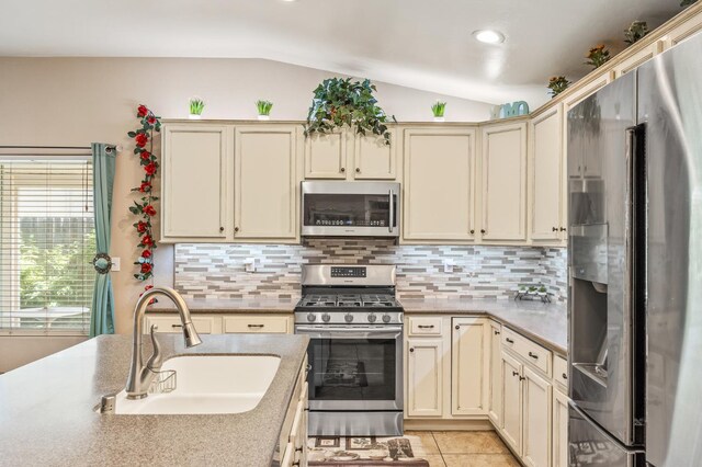 3624 N Jackie, Visalia, CA 93291 - kitchen with stainless steel appliances, vaulted ceiling, cream cabinets, decorative backsplash, and light tile patterned floors