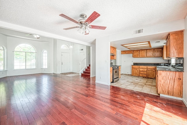 3340 N Dante Ave, Fresno, CA 93722 - kitchen featuring dark countertops, stainless steel range oven, brown cabinets, open floor plan, and light wood finished floors